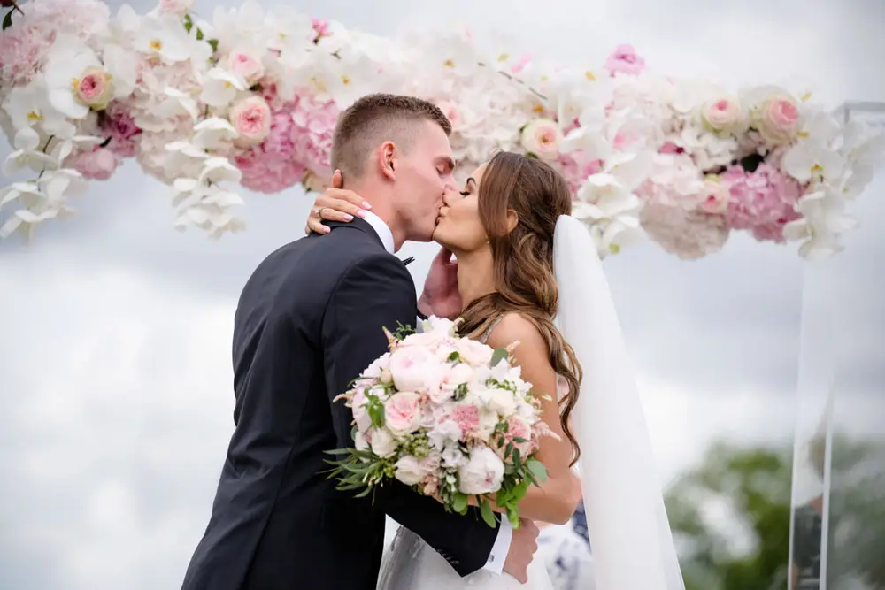 První novomanželský polibek pod bohatě zdobenou slavobránou