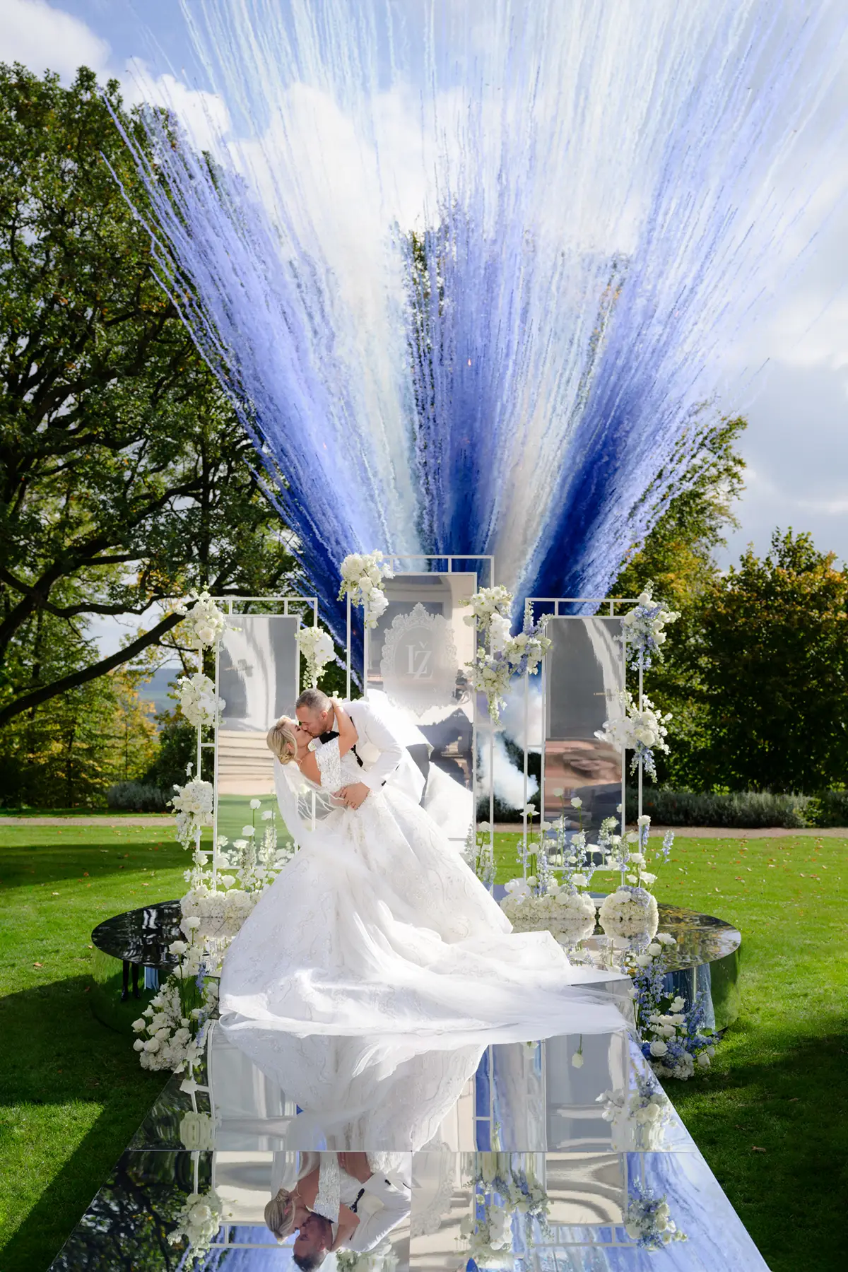 Nevěsta s ženichem si dávají první pusu na zrcadlovém mole s barevným ohňostrojem v pozadí na svatbě u Prahy