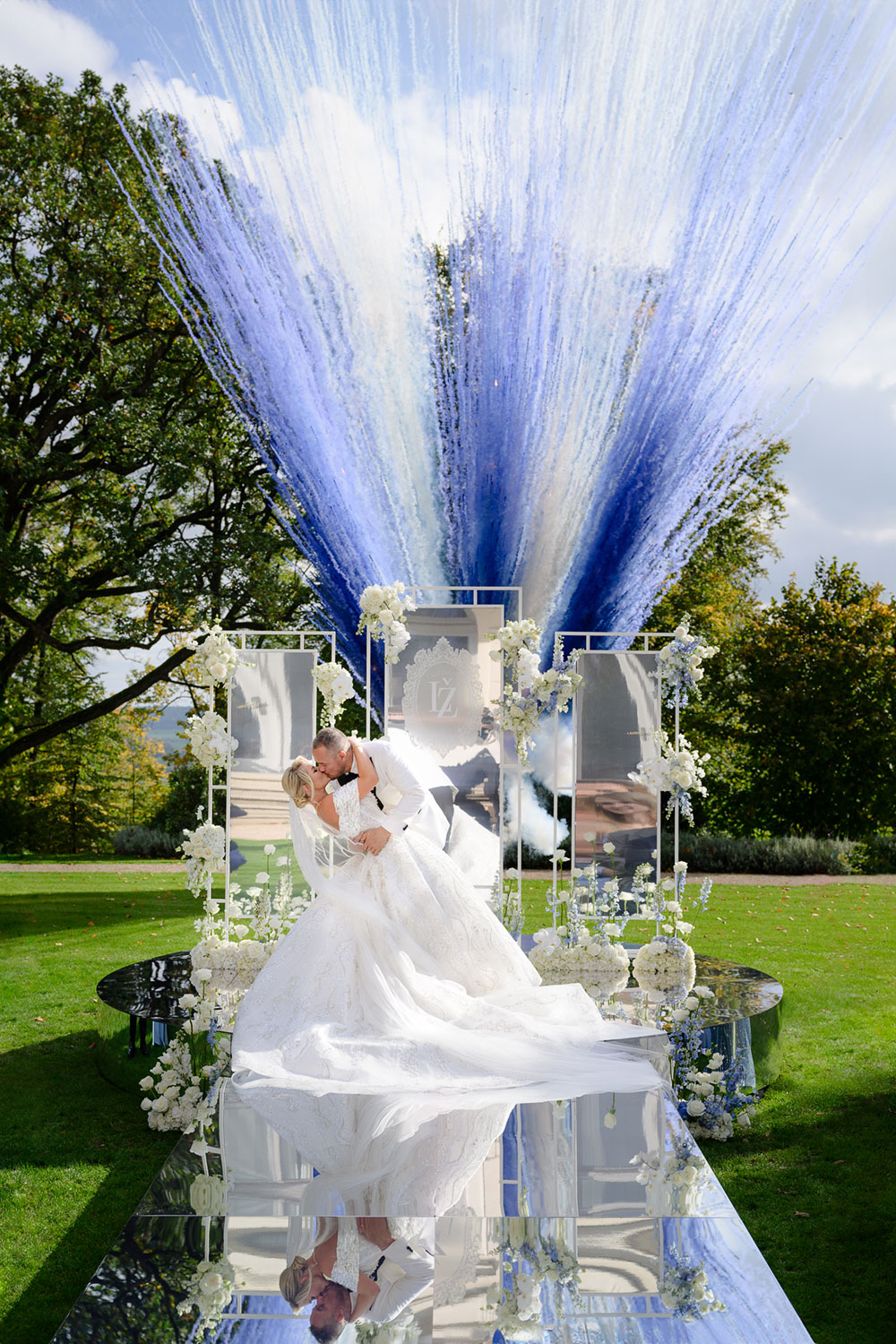 Nevěsta s ženichem si dávají první pusu na zrcadlovém mole s barevným ohňostrojem v pozadí na svatbě u Prahy