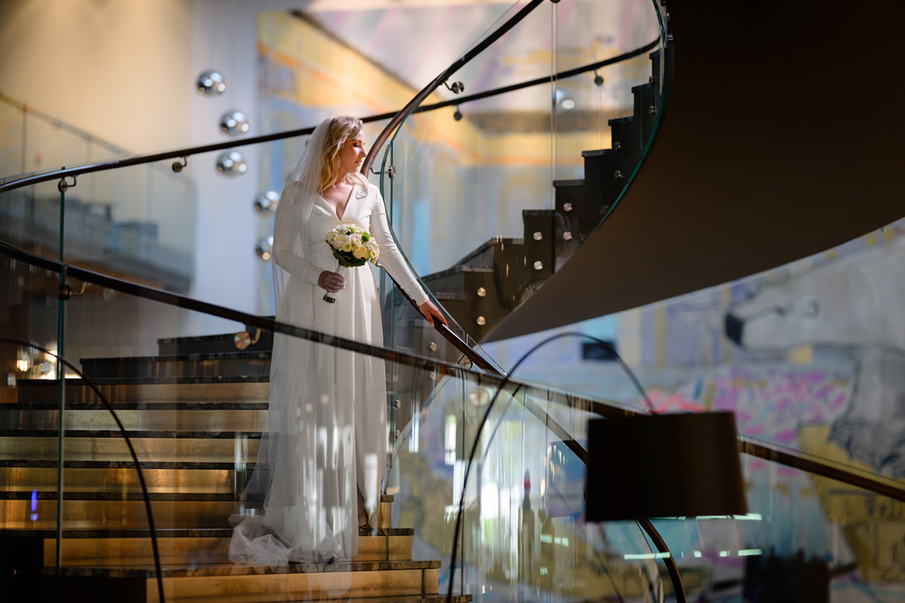 bride holding bouquet on the stairs in Brno hotel Courtyard Marriott