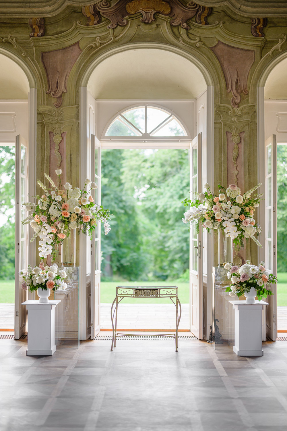 Ornate interior of Bon Repos with floral arrangements and grand doors opening to lush greenery, perfect for a luxury wedding.