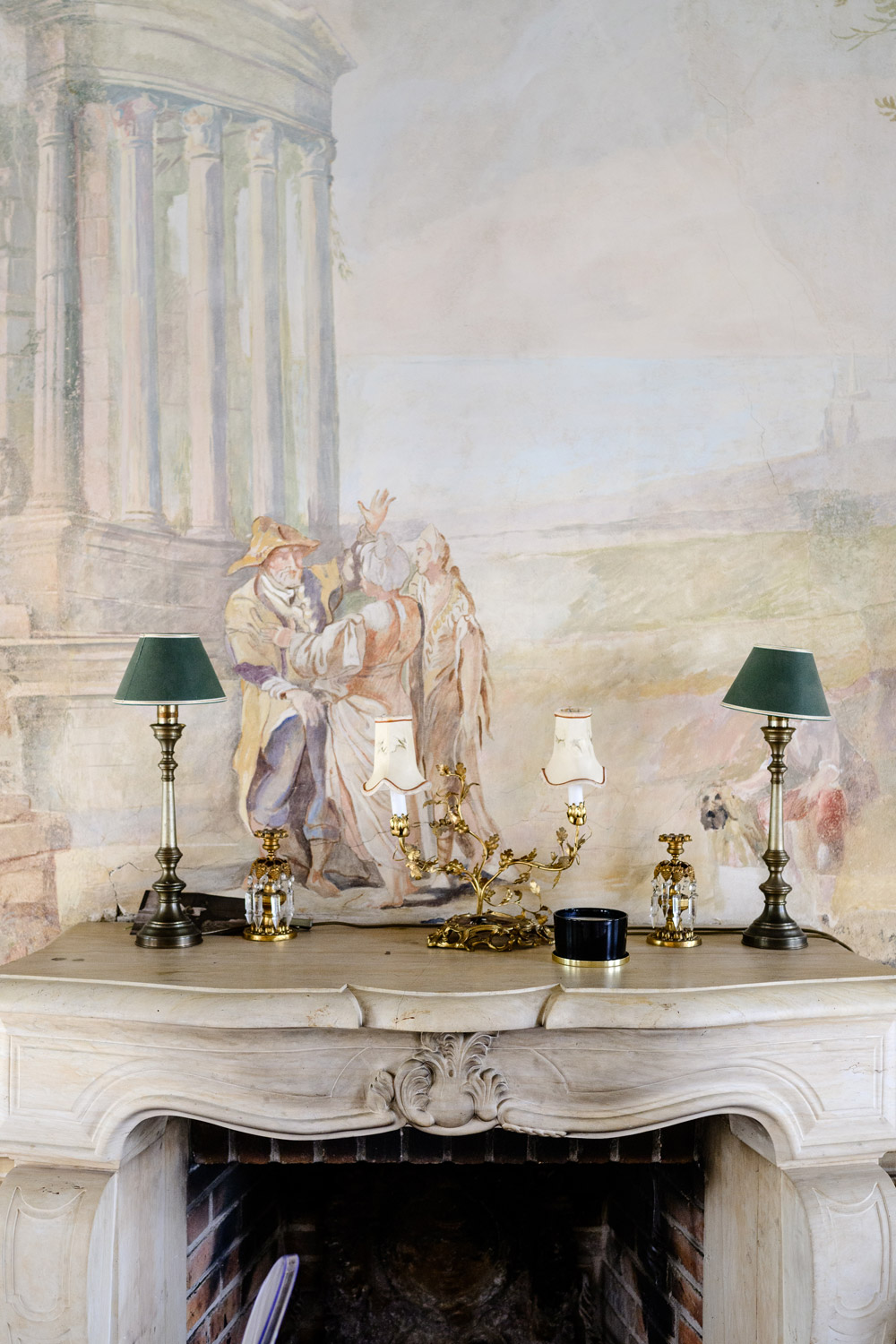 Elegant fireplace adorned with classical art and decorative candles, set in a luxurious Czech wedding venue, Bon Repos.