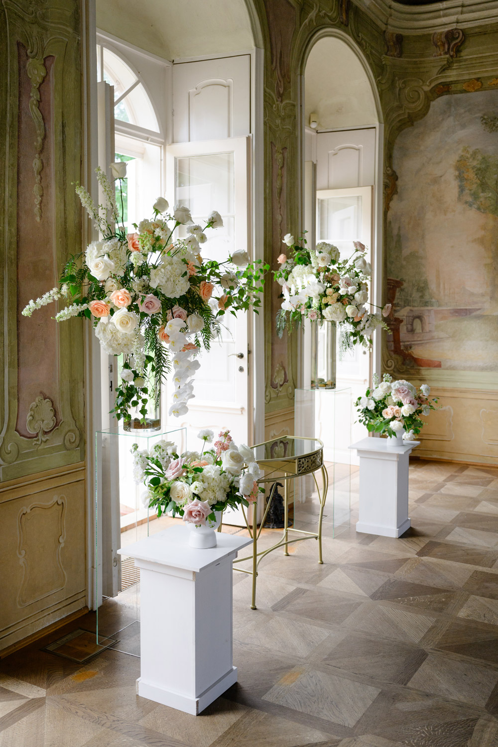 Elegant floral arrangements in a luxurious Czech wedding venue, Bon Repos, with tall vases and a vintage table.