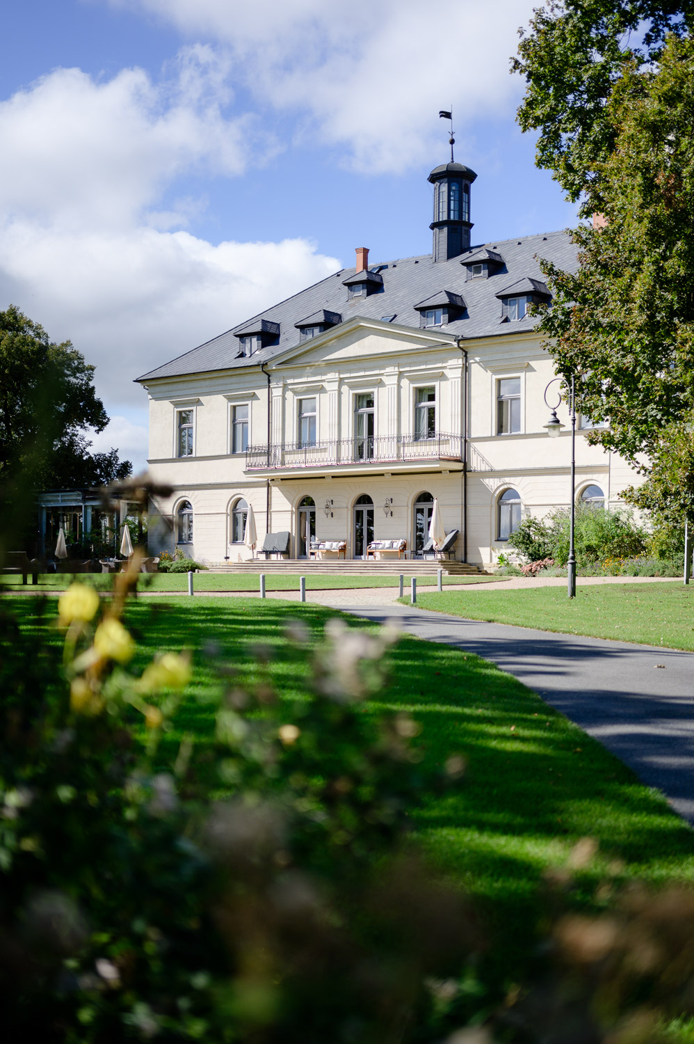 Exterior view of Chateau Mcely, a luxurious venue with a well-maintained garden and outdoor seating area, perfect for weddings and events.