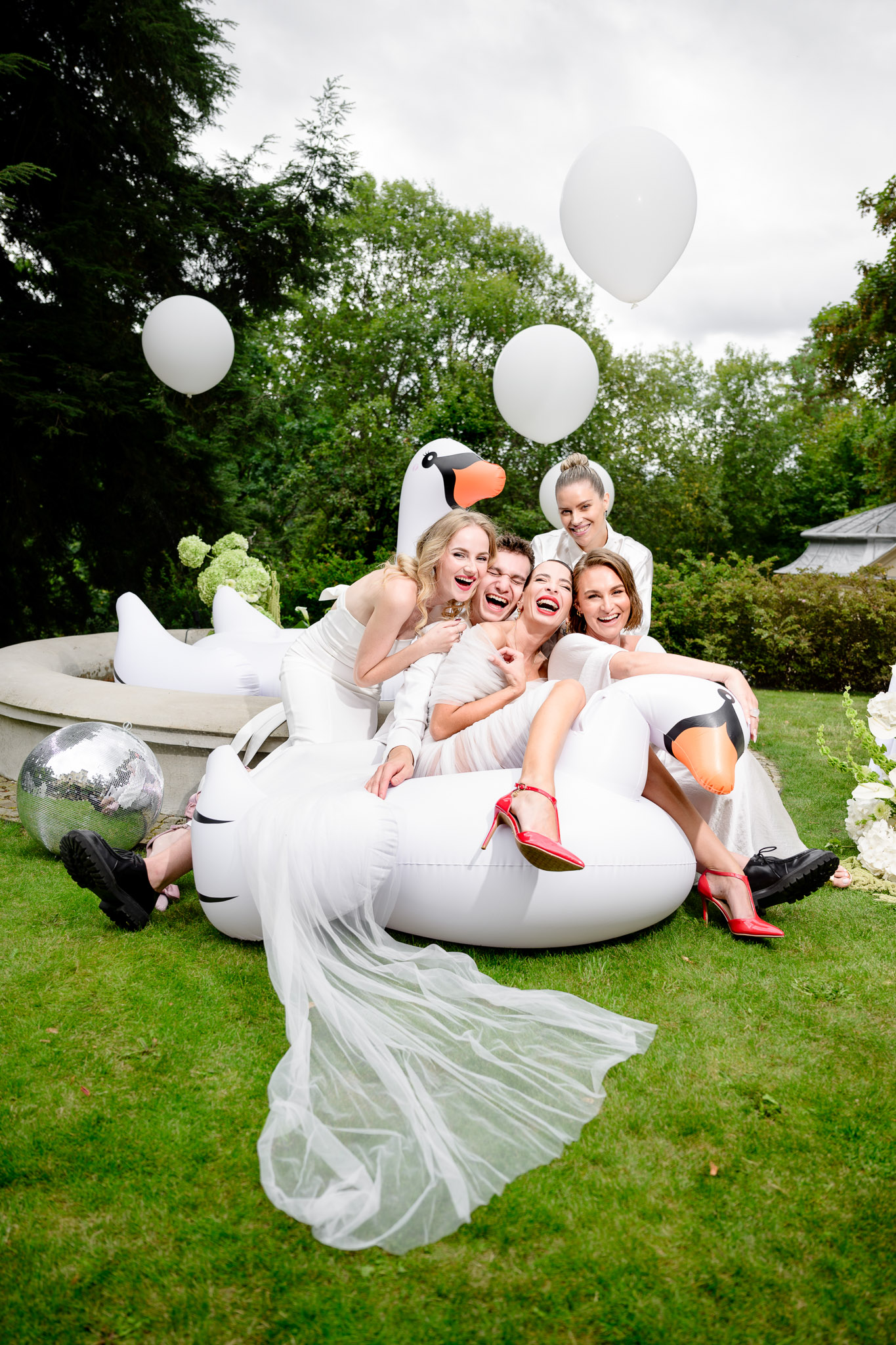 Debbie Brown’s wedding: the fashion designer celebrating with her guests on an inflatable swan seat in the villa garden. A joyful atmosphere with balloons and a disco ball.