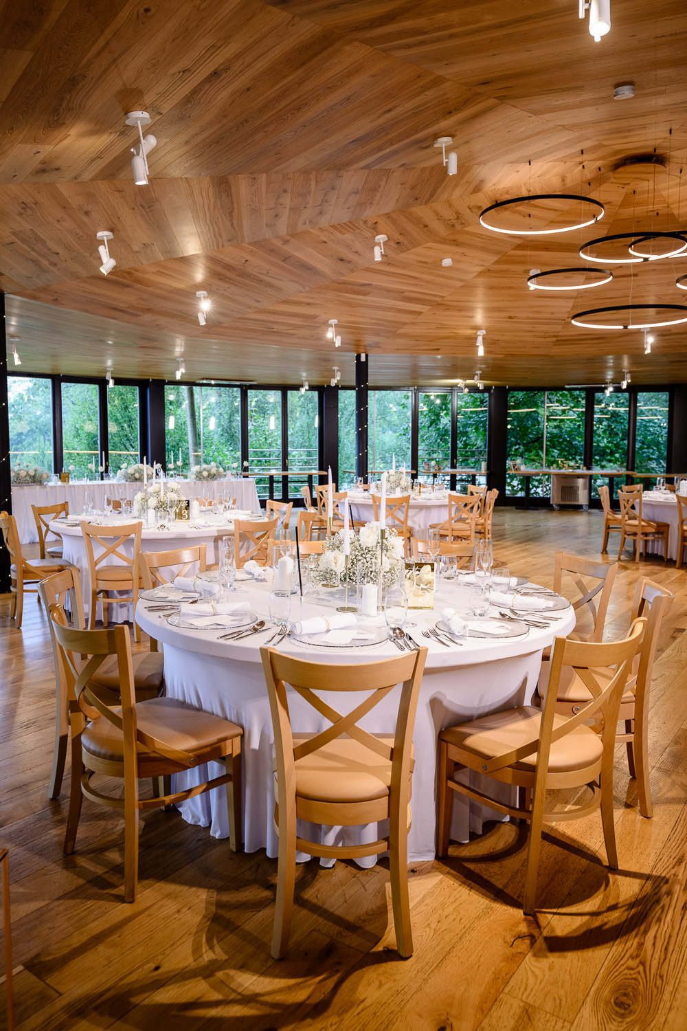 Wedding reception at the Cattalaya resort: elegantly set round tables, wooden chairs, and a view of the greenery.