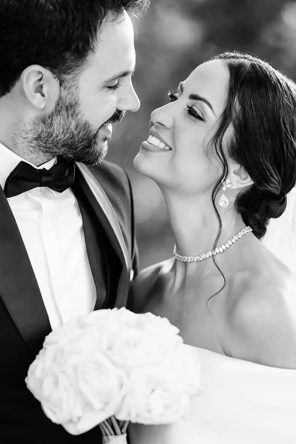 Black-and-white photograph of the bride and groom smiling at each other.