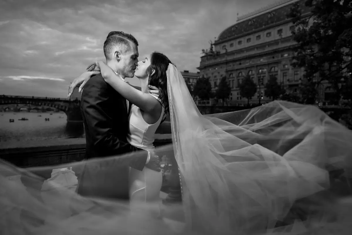 Černobílá novomanželská fotografie s atmosférou staré Prahy před Národním divadlem.