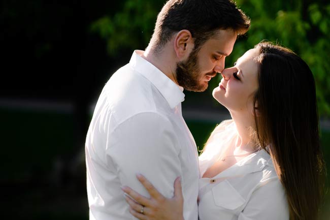 woman with long dark hair holding tight a man in white shirt and almost kissing during pre wedding photoshoot in prague 