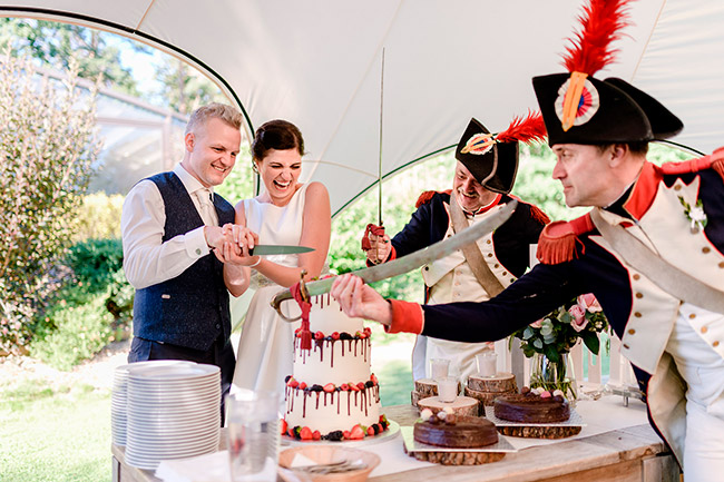 nevěsta a ženich krájí dort a vojácí podávají šavle