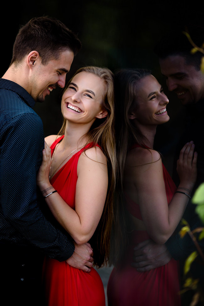 woman in red dress smiling and holding man in shirt smiling at her during prague prewedding photoshoot 