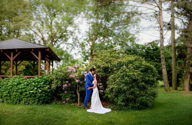 nevěsta s ženichem uprostřed zelené zahrady s vysokými stromy svatba mlýn vodníka slámy