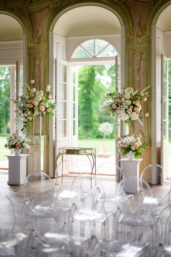 Beautiful floral displays and transparent seating in the luxurious Bon Repos wedding venue, with a view of the garden.