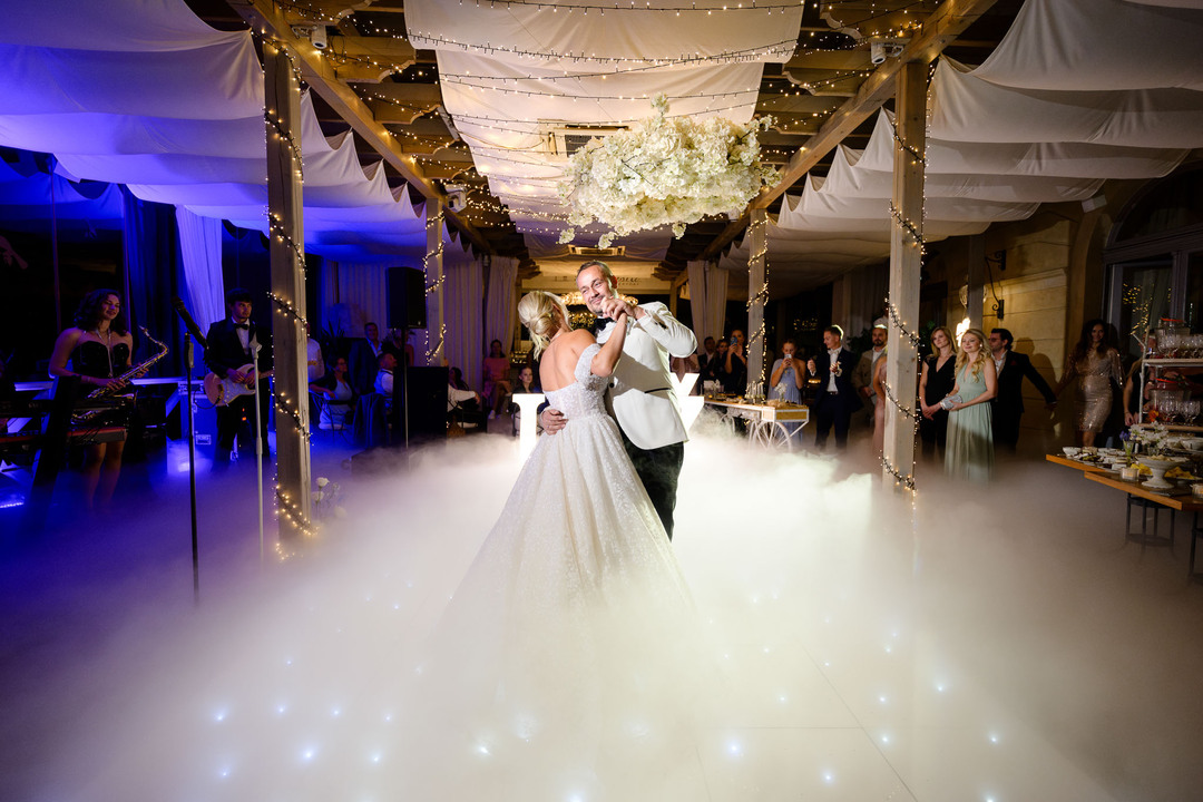 Bride and groom sharing their first dance under a beautifully decorated canopy at Chateau Mcely, surrounded by guests enjoying the magical moment.