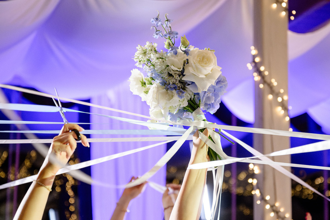 Bridal bouquet held aloft by ribbons against a backdrop of fairy lights at a magical Chateau Mcely wedding.