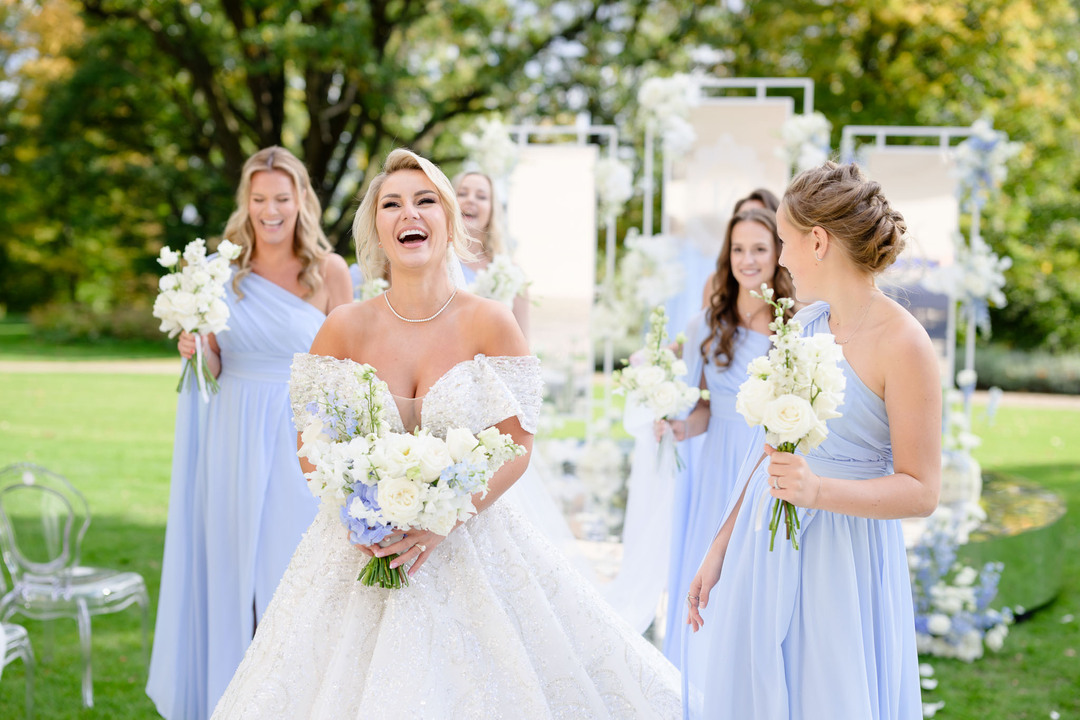 Bride laughing with bridesmaids in blue dresses at Chateau Mcely wedding.
