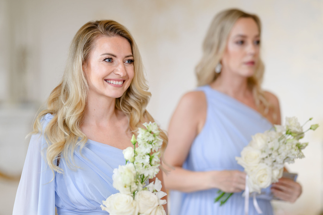 Smiling bridesmaids in elegant lavender dresses holding white flower bouquets at a wedding at Chateau Mcely.