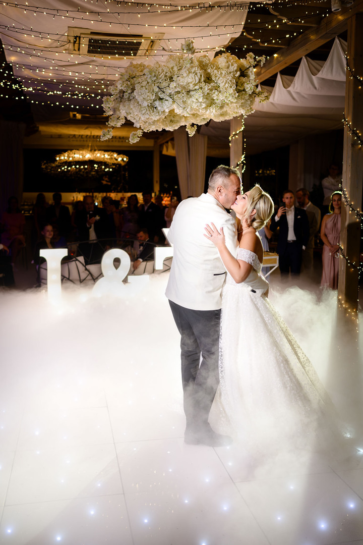 Romantic first dance of the bride and groom under a floral chandelier.