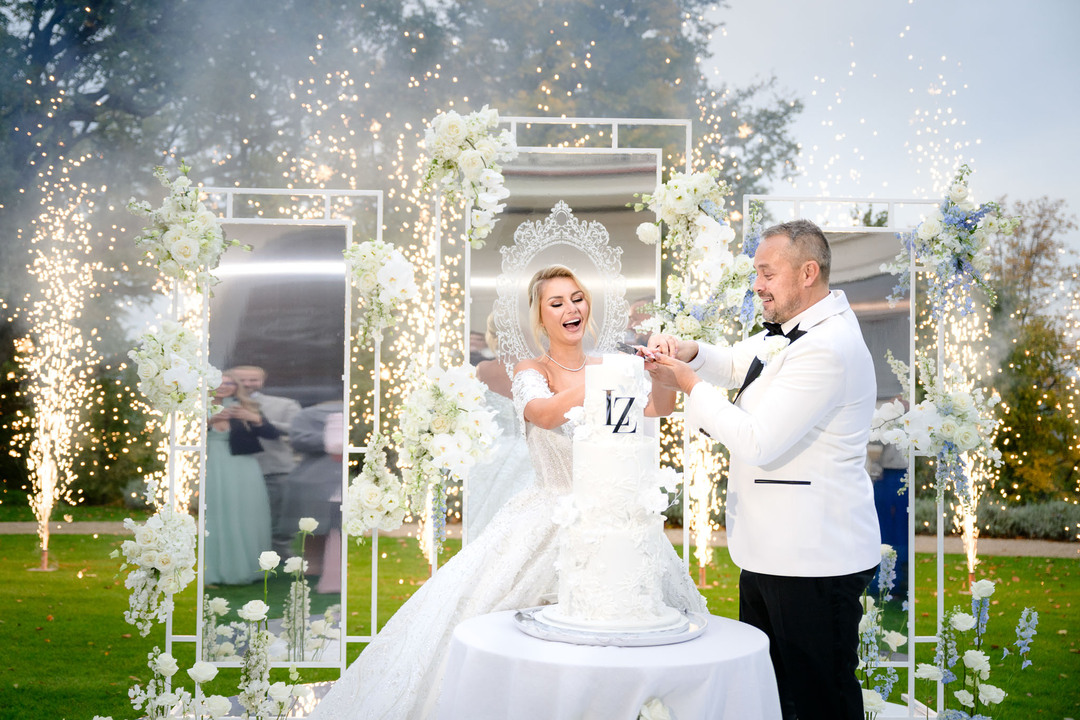 Bride and groom cutting their wedding cake at Chateau Mcely, surrounded by elegant floral arrangements.