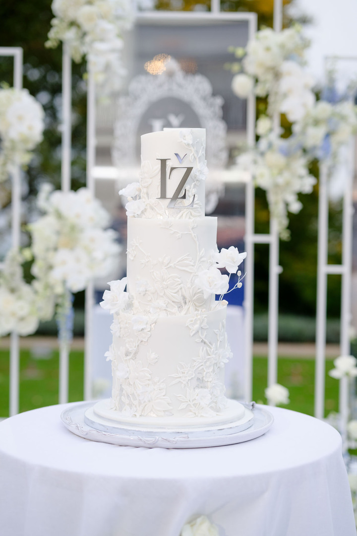 Beautiful white wedding cake with intricate floral details and initials at Chateau Mcely.