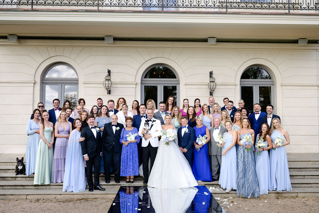 Elegant wedding party posing in front of the luxurious Chateau Mcely.