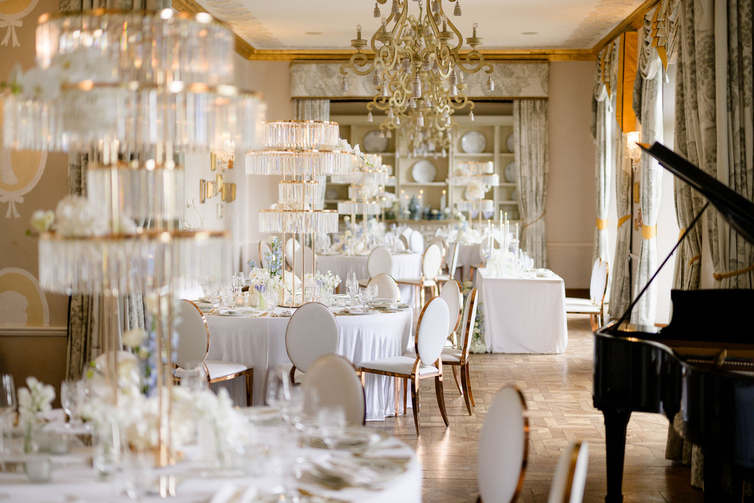 Elegant wedding reception at Chateau Mcely with a beautifully set dining table, crystal decorations, and a grand piano.