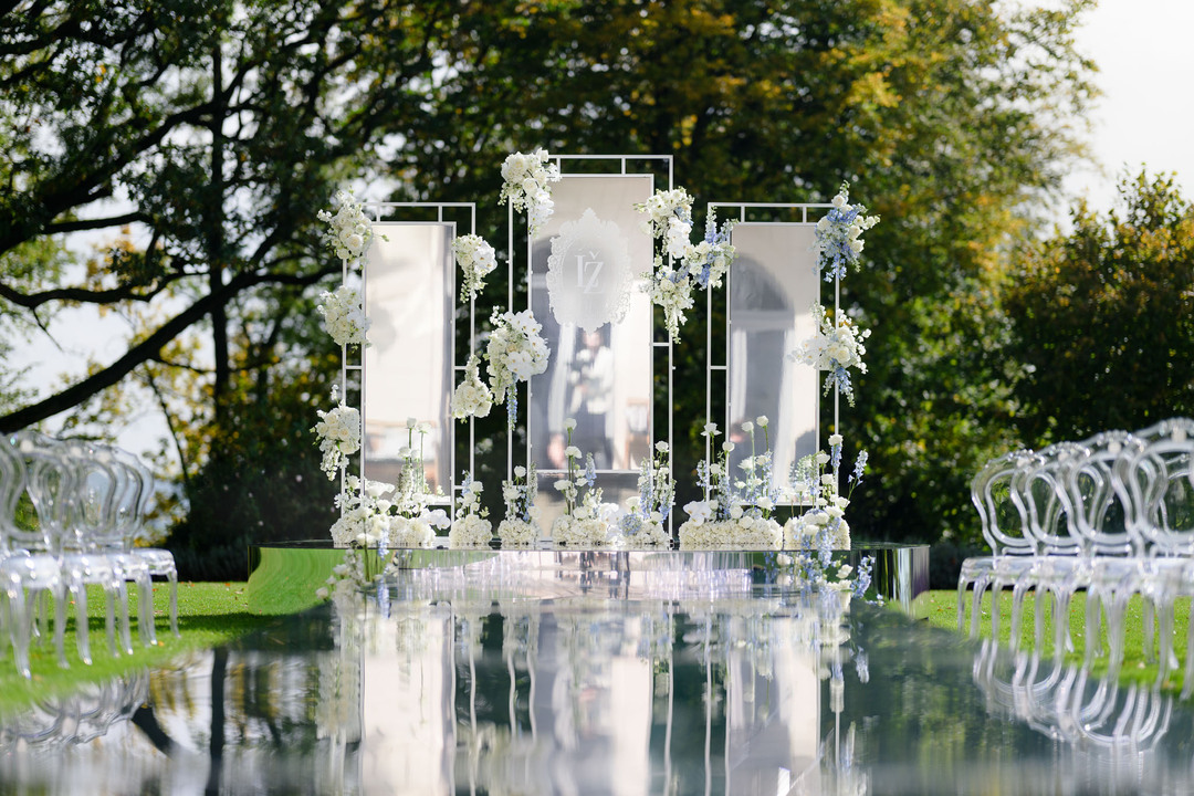 Outdoor wedding ceremony setup at Chateau Mcely with a reflective aisle, floral decorations.