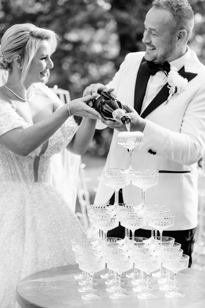 Bride and groom pouring champagne into a tower of glasses at Chateau Mcely.