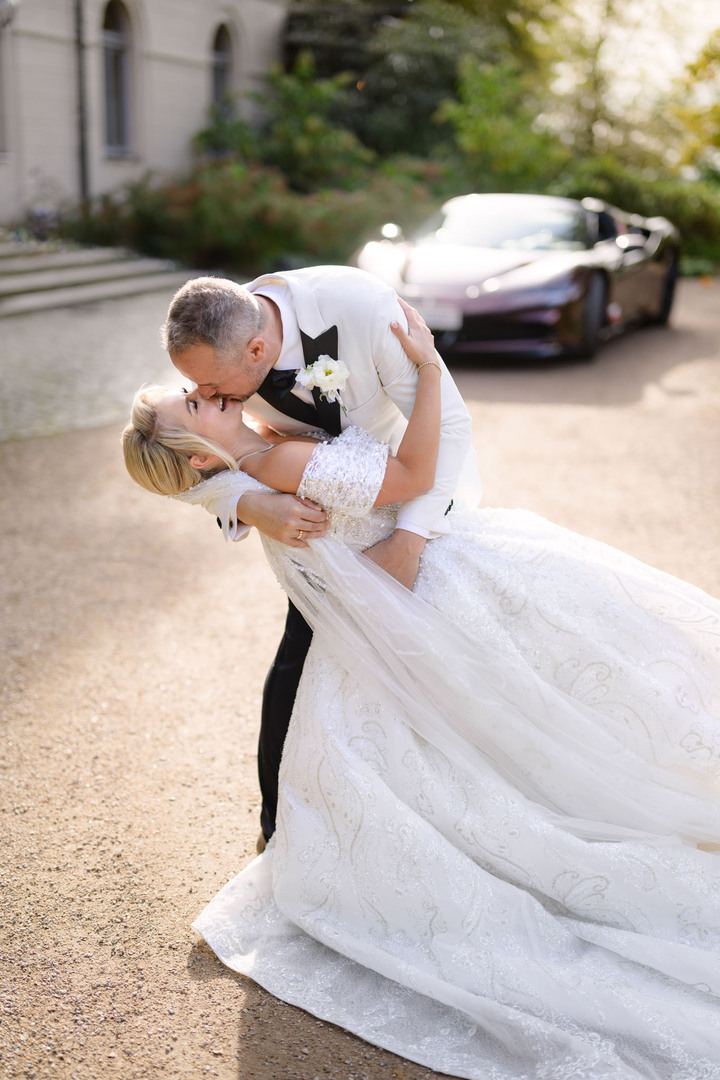 Bride and groom kissing in front of a luxury car at Chateau Mcely.