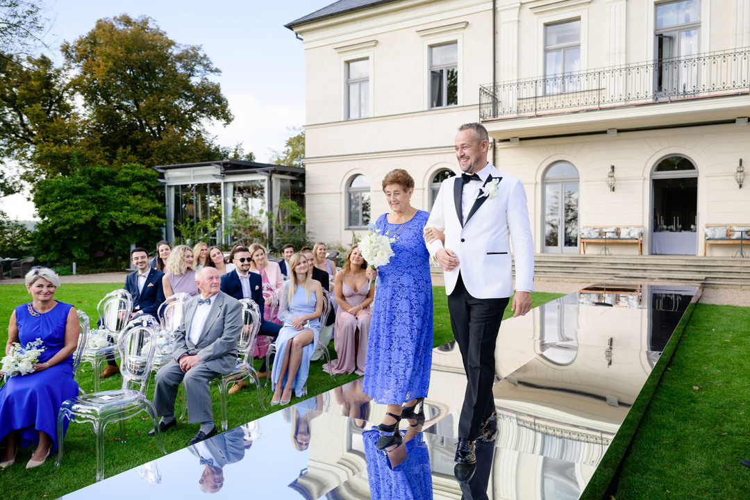 Groom accompanied by his mother walking down the aisle at a luxury Chateau Mcely wedding.