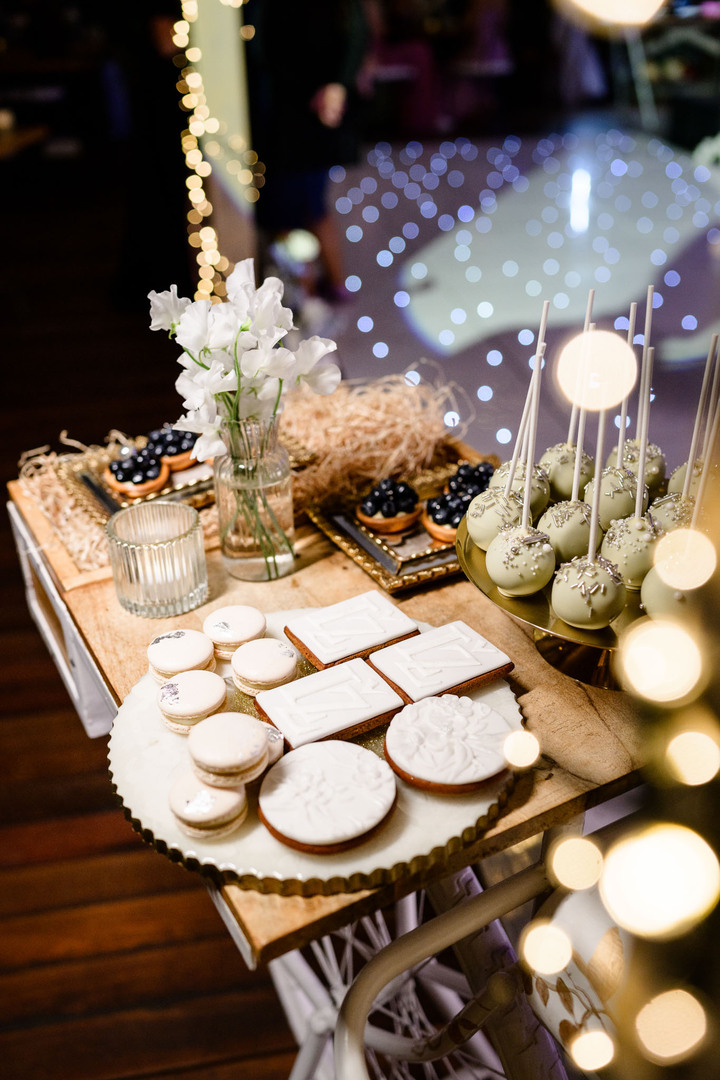 Elegant dessert table with macarons, cake pops, and cookies artfully arranged for a chateau wedding reception.