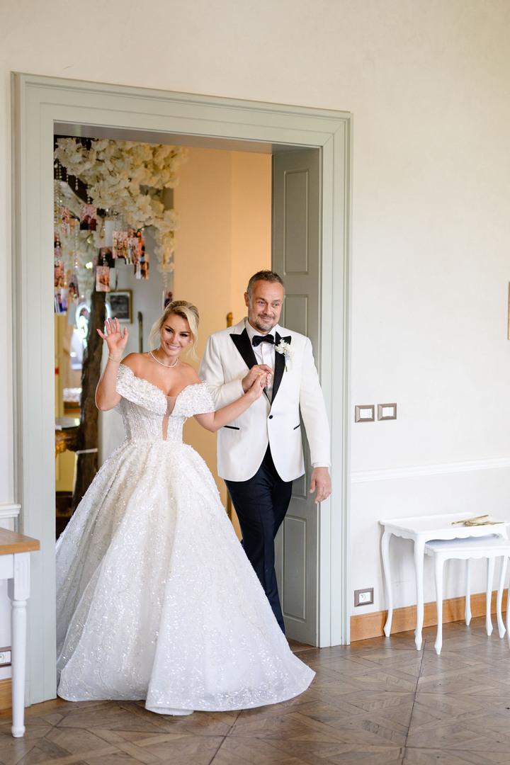 Joyful bride and groom entering a beautifully decorated room at Chateau Mcely, radiating happiness on their wedding day.