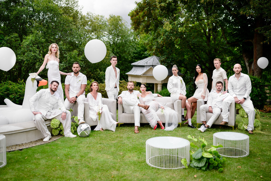The newlyweds with their guests, all dressed in white, pose for a group photo in the garden of Villa Julius & Emma P. in Karlovy Vary.
