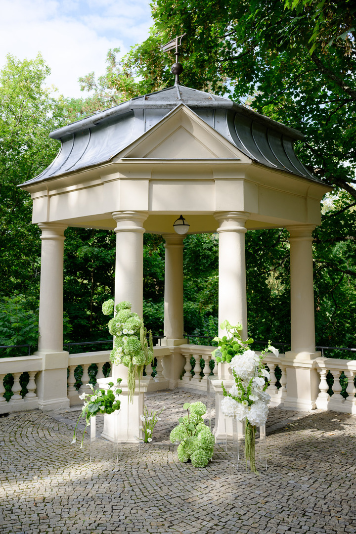 A wedding gazebo at Villa Julius & Emma P. in Karlovy Vary, decorated with green and white flowers.
