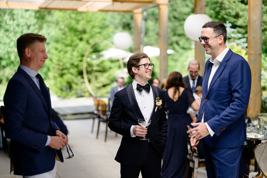 The groom chatting with wedding guests in the morning under the covered terrace in front of Hotel & Garden U Holubů in Čeladná.
