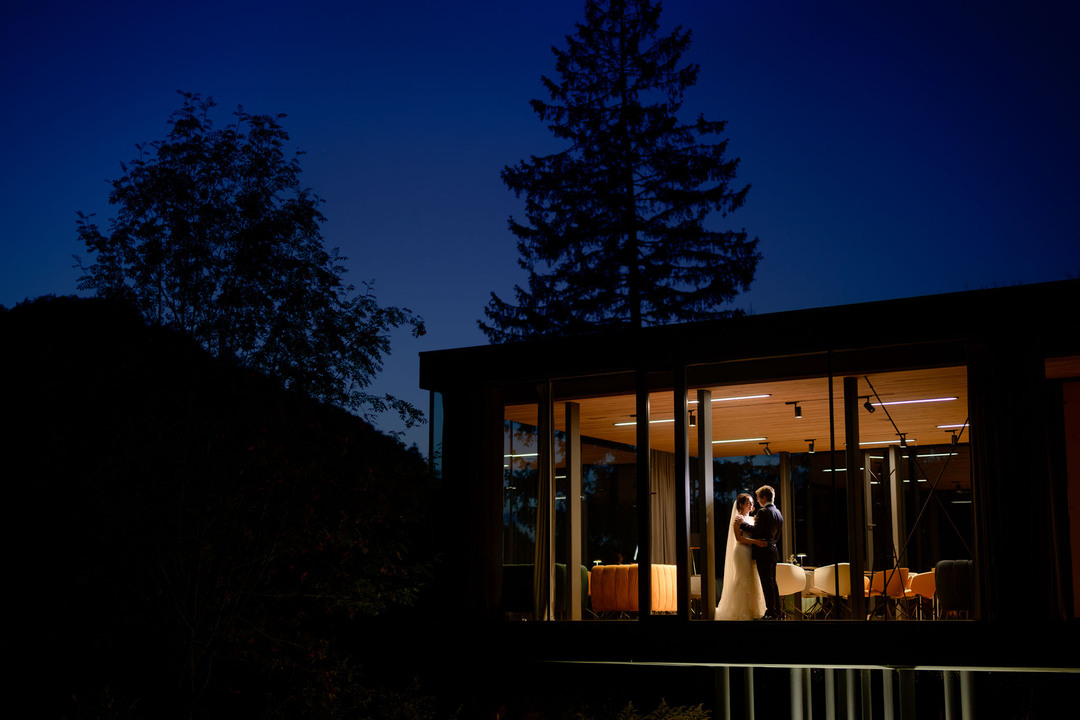 The newlyweds glowing in the soft light of the glass winter garden at U Holubů, a dreamy and intimate evening wedding moment in the Beskydy, photographed by Jindřich Nejedlý.
