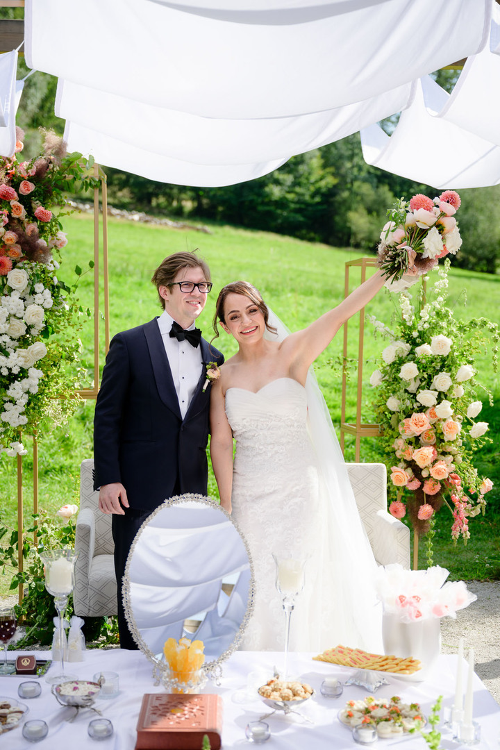 The bride and groom joyfully celebrate their completed ceremony under the outdoor arch at Hotel & Garden U Holubů in Čeladná.
