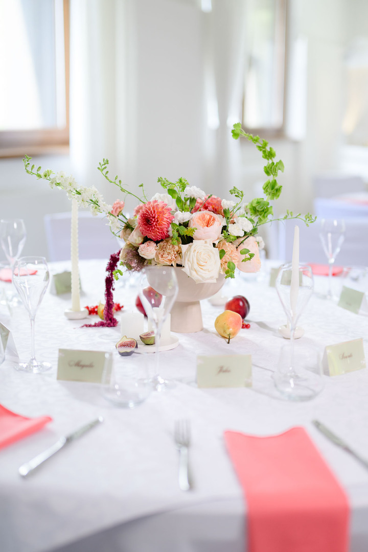 Set table with elegant floral decoration featuring roses and dahlias, surrounded by sparkling glassware and place cards, a stylish wedding detail at U Holubů.
