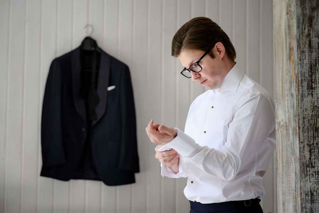 Wedding preparations in a room at U Holubů, the groom putting on his shirt.

