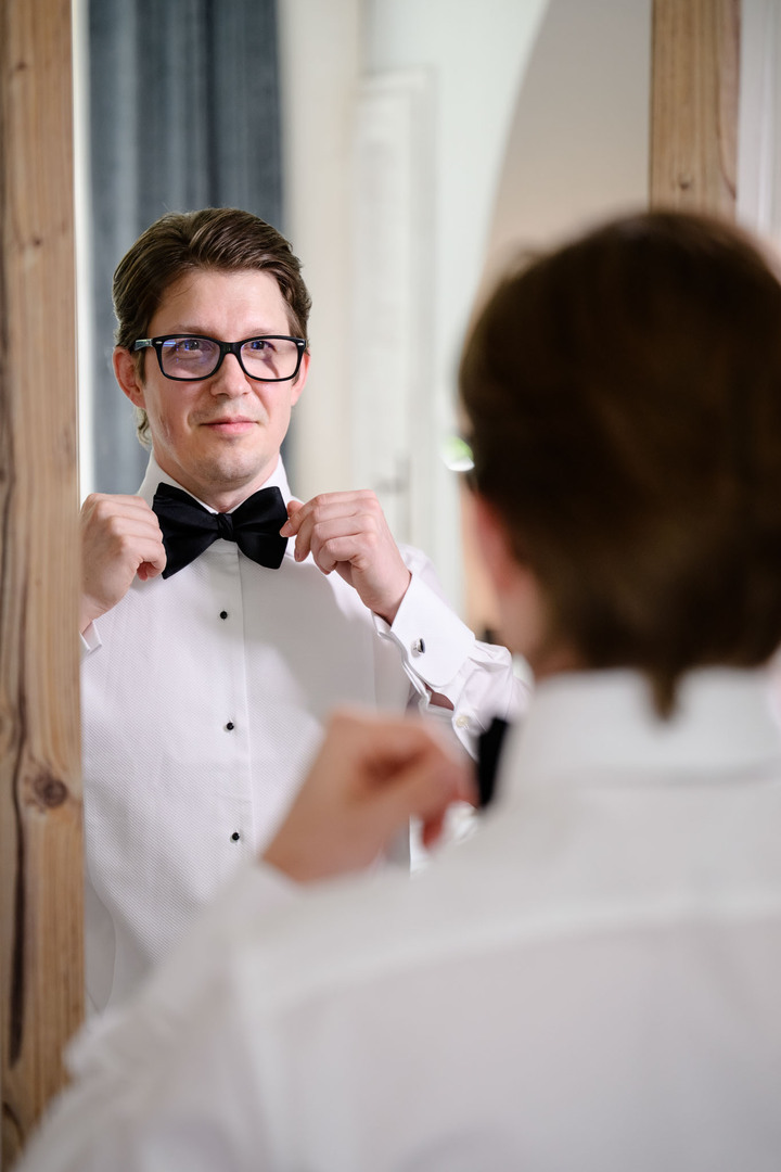The groom tying his bow tie, photographed by Jindřich Nejedlý in Čeladná.
