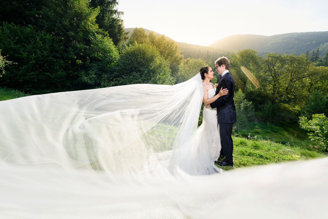 Love in motion as newlyweds embrace at sunset, the bride’s veil flowing in the wind amid the Beskydy landscape, photographed by Jindřich Nejedlý.