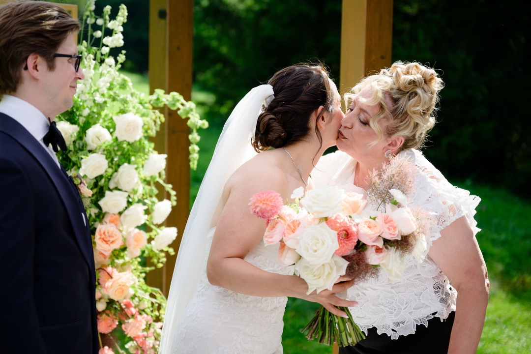 The groom’s mother hugs and kisses her new daughter on the cheek.
