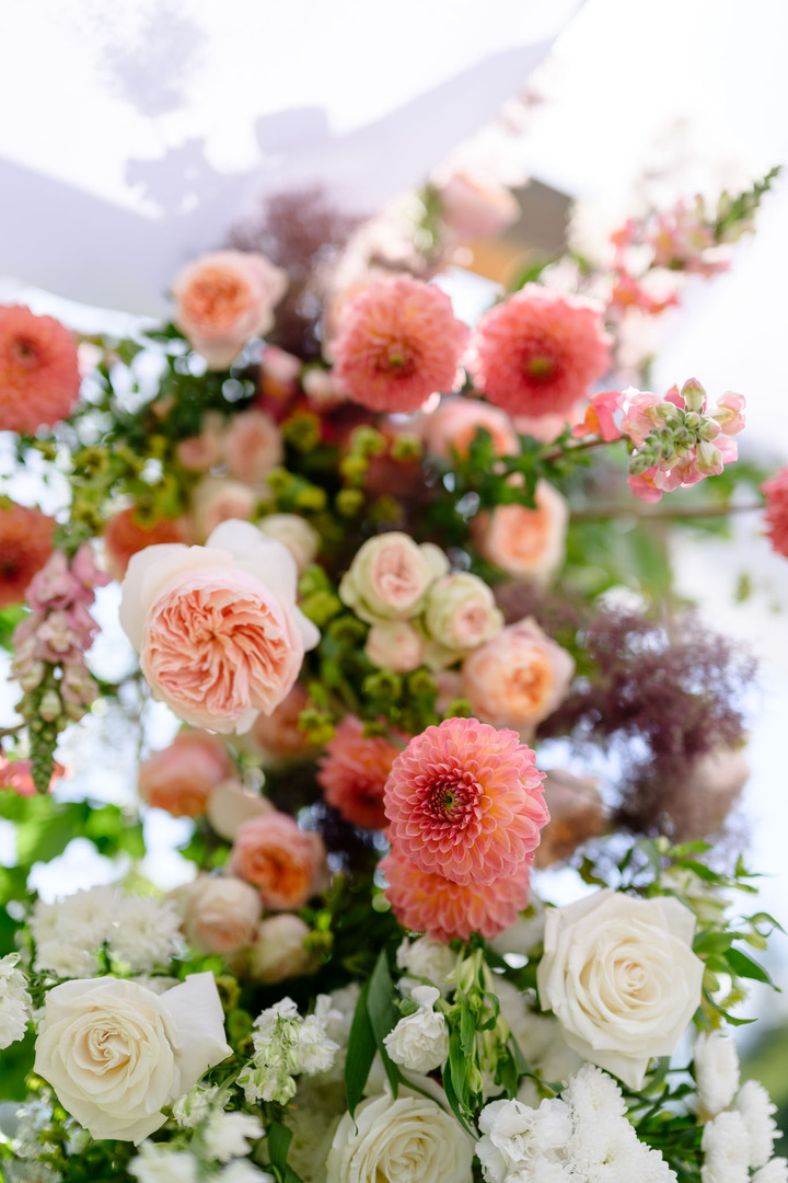 Detailed photograph of outdoor floral arrangement with pink and orange flowers complemented by white roses.
