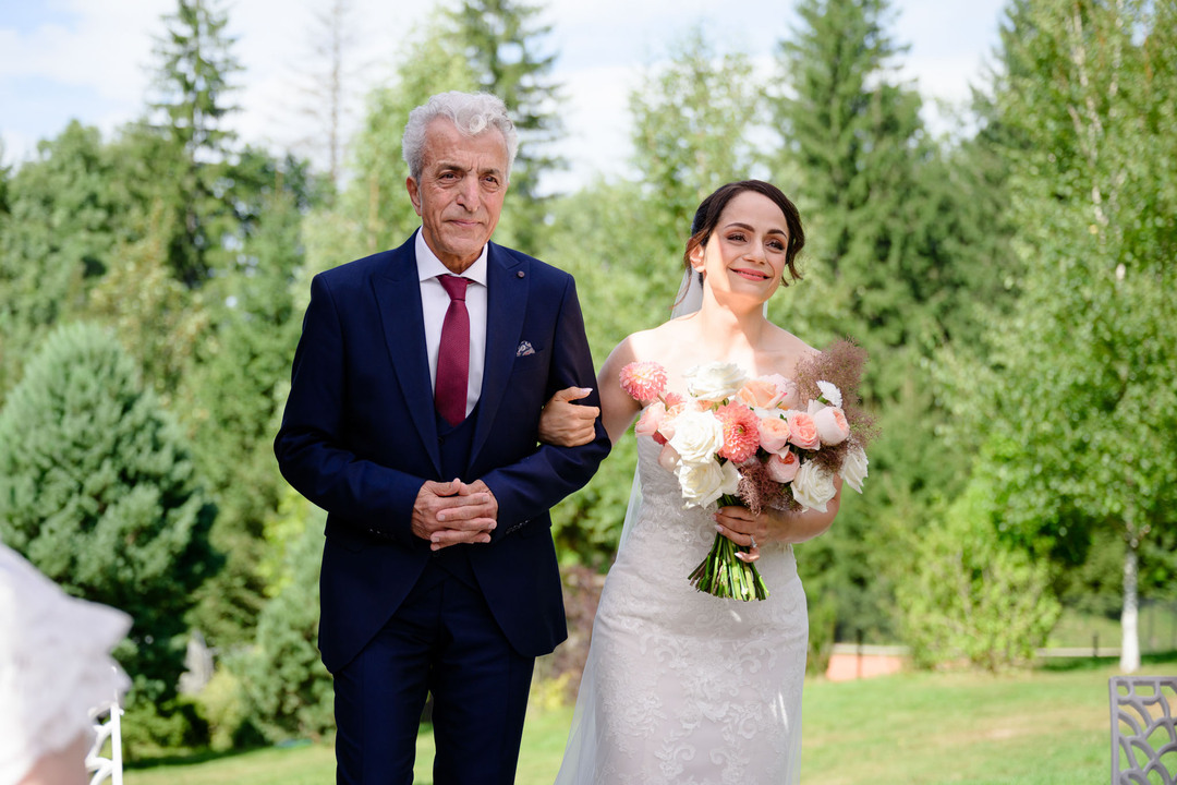 The bride walks to the wedding ceremony escorted by her father during a wedding in the Beskydy.
