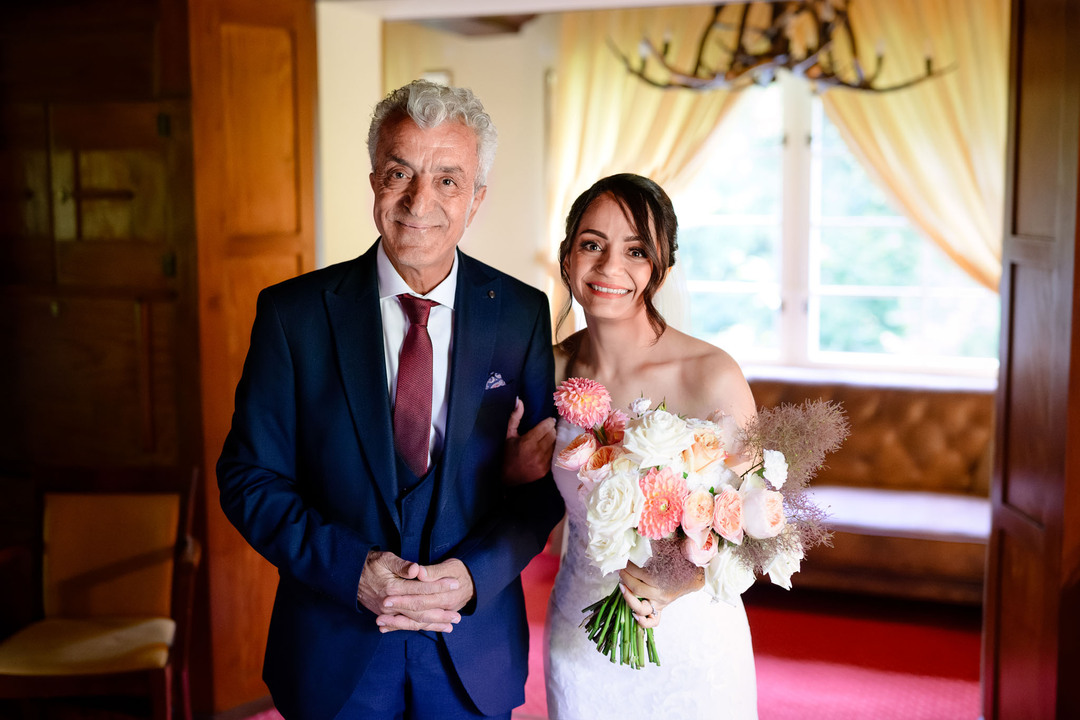 The bride and her father posing for a photograph in a room at U Holubů.
