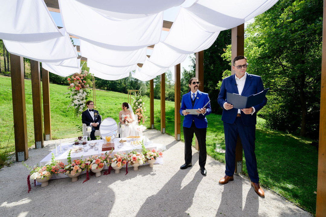 Outdoor wedding ceremony at U Holubů under a shaded pergola.
