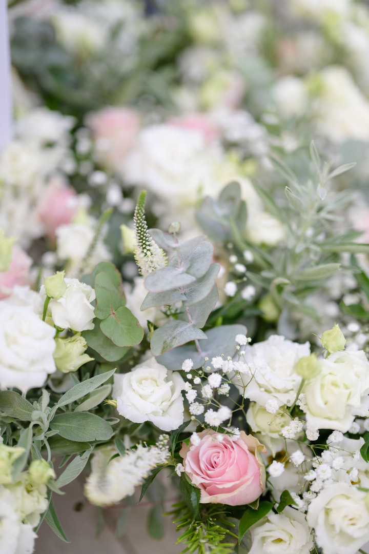 Blízký záběr na světlou květinu složenou z bílé a růžové růže, šateru, eucalyptu, rozrazilu a jícnovky. Dohromady vypadají krásně jemně a něžně.