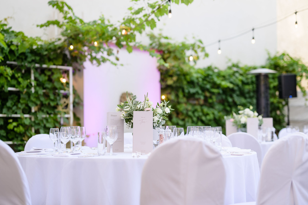 Elegantní dekorace a něžné květiny na stolech prostřených k recepci.