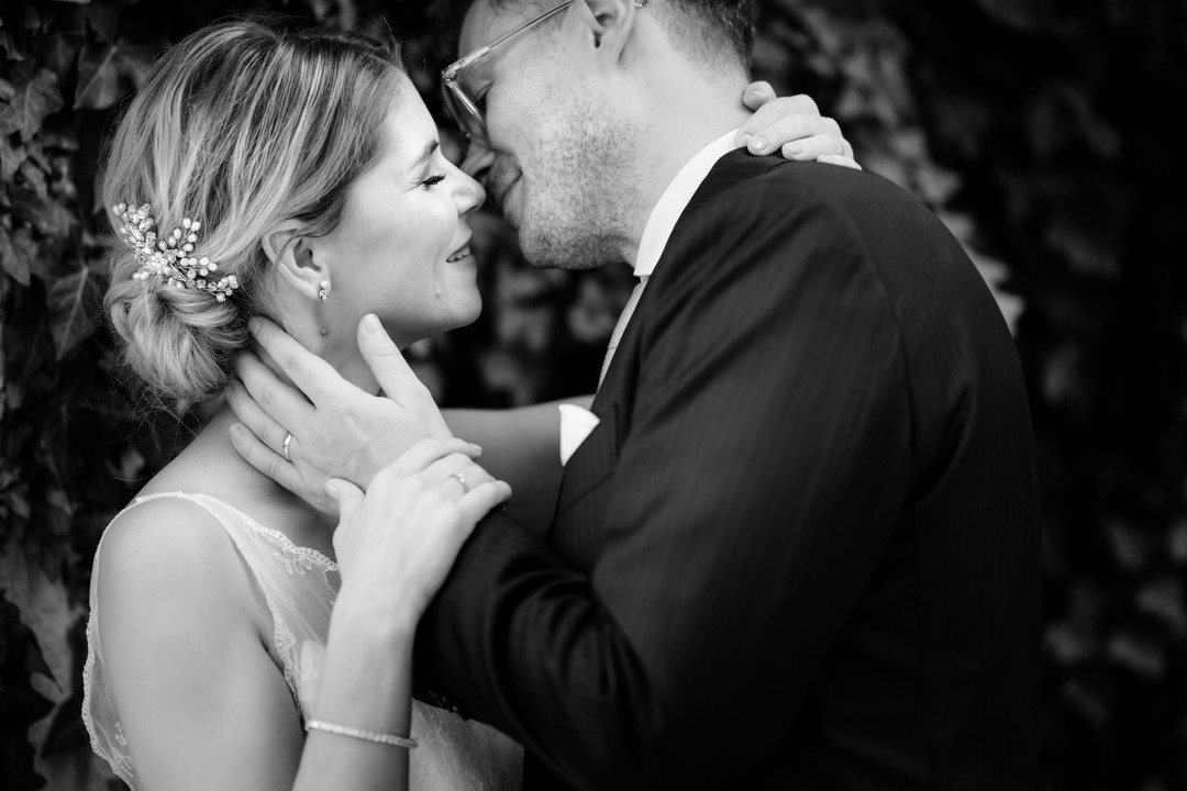 Blízký záběr na novomanžele, vzájemně se dotýkají, obličeje mají blízko sebe a chystají se políbit.