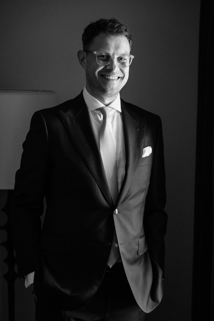 Ženich pózuje a směje se na této černobílé fotografii.